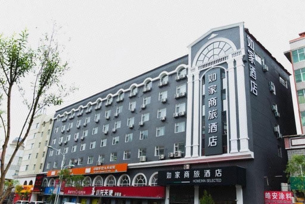 A hotel building with multiple floors, a prominent entrance with a curved facade, and several ground-level shops.