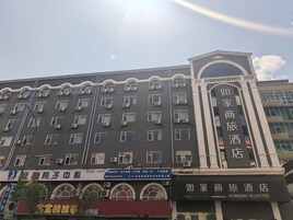 Un hotel con varios pisos, unidades de aire acondicionado y un letrero destacado que dice 'Homeinn Selected'.