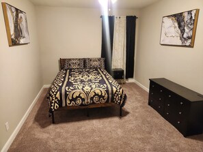 A bedroom with a bed, a dresser, and two paintings on the walls. - Spacious 4-bedroom house in pleasant Columbia with AC (Columbia)