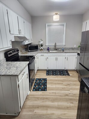 A kitchen with white cabinets, a stainless steel refrigerator, a microwave, and a stove. - Spacious 4-bedroom house in pleasant Columbia with AC (Columbia)