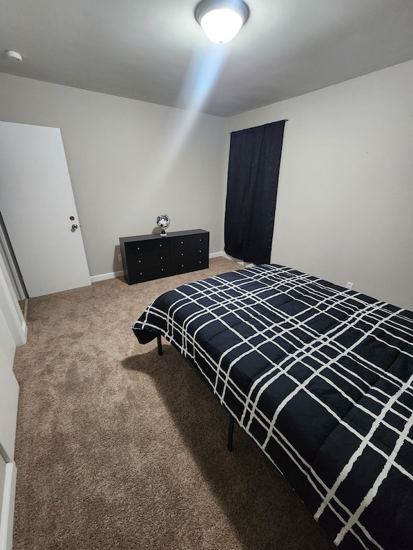 A bedroom with a bed, a dresser, a globe, and a door. - Spacious 4-bedroom house in pleasant Columbia with AC (Columbia)