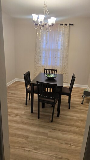 A dining area with a table, chairs, a chandelier, and a window with curtains. - Spacious 4-bedroom house in pleasant Columbia with AC (Columbia)
