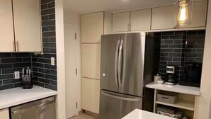 A modern kitchen with stainless steel appliances, a dishwasher, and a white countertop. - Park City Condo – Pool, Hot Tub & Waffles (Park City)