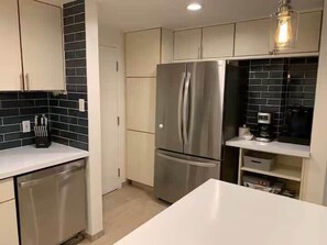 A modern kitchen with stainless steel appliances, a dishwasher, and a white countertop. - Park City Condo – Pool, Hot Tub & Waffles (Park City)