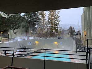 A pool area with a view of trees and a building in the background. - Walk to lifts · Old Town condo, pool & hot tub (Park City)