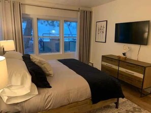 A bedroom with a bed, a TV, a dresser, and a window with a view of a snowy landscape. - Park City Condo – Pool, Hot Tub & Waffles (Park City)