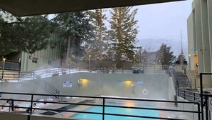 A pool area with a view of trees and a building in the background. - Park City Condo – Pool, Hot Tub & Waffles (Park City)