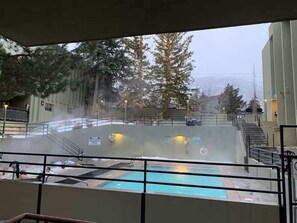 A pool area with a view of trees and a building in the background. - Park City Condo – Pool, Hot Tub & Waffles (Park City)