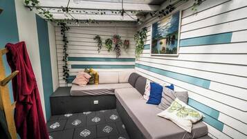 A cozy room with a sofa, a bench, and a wall with plants and a painting.