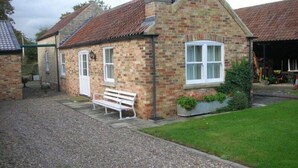 A brick house with a gravel driveway, a white bench, and a garden area. - Watermill Farm (Lincoln)