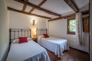 Une chambre avec deux lits simples, une fenêtre avec des rideaux et un plafond en bois.