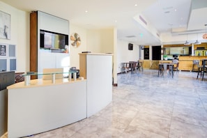 A modern hotel lobby with a reception desk, seating area, and a bar.