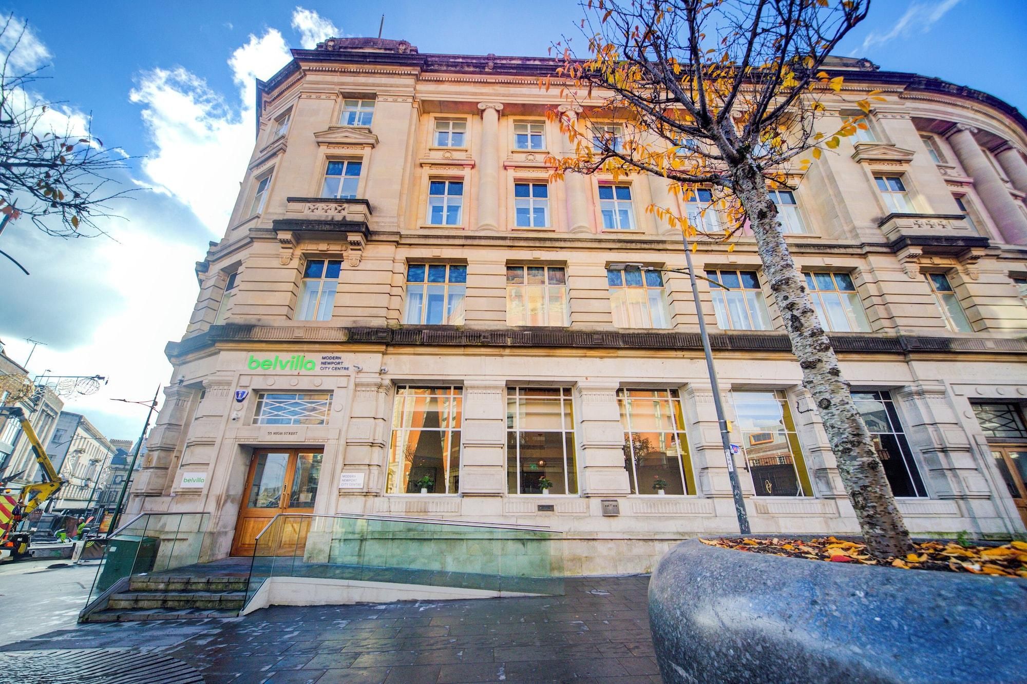 Un edificio histórico con un letrero del moderno centro de la ciudad, grandes ventanales y un árbol en primer plano.