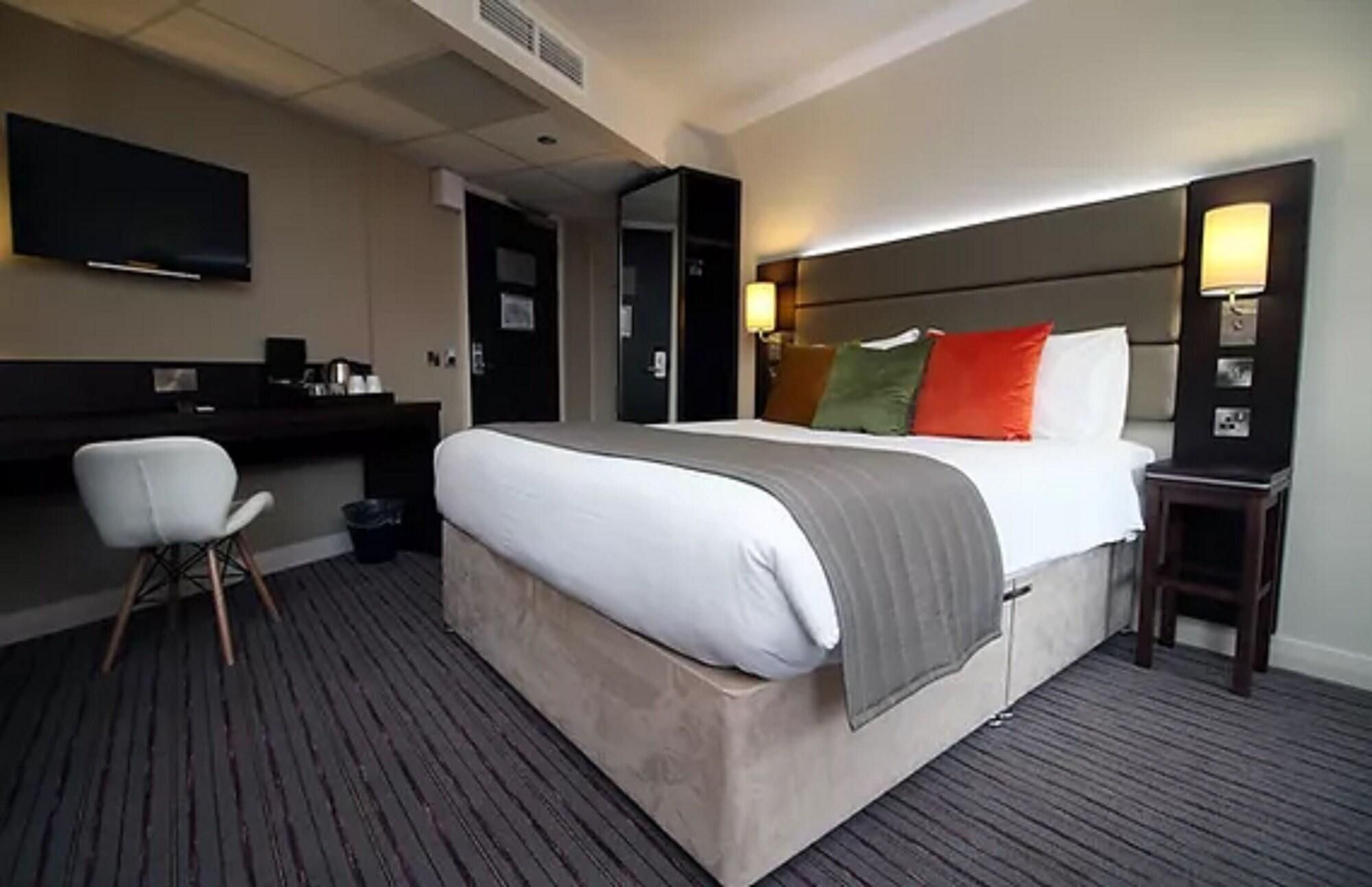 Una habitación de hotel con cama, escritorio, silla y televisión.