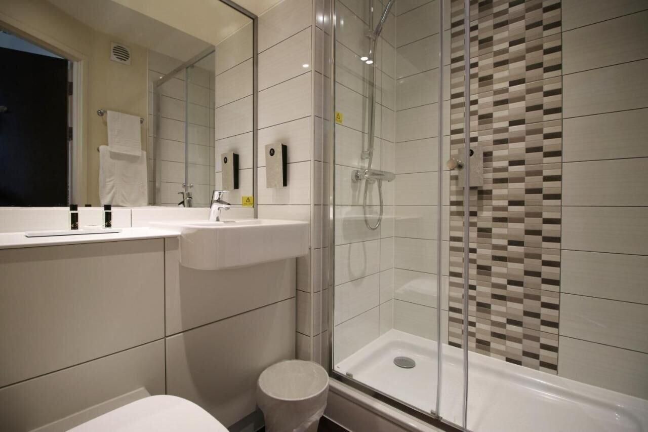 Un bany modern amb dutxa amb envidriament, un lavabo blanc i un vàter.