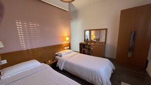A hotel room with two beds, a desk with a chair, a mirror, and a wardrobe. - Hotel Green House (Berat)