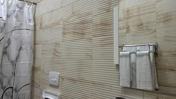 Un baño con cortina de ducha, inodoro, lavamanos y toallero.