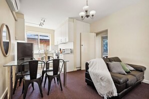 A compact living space with a kitchenette, dining area, and seating area. - Domi Rentals - The Carlisle Street Apartments (Balaclava)