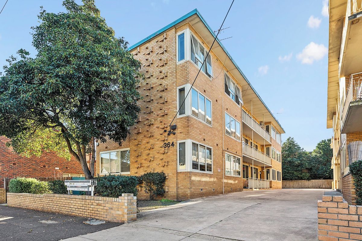 A multi-story residential building with a brick facade, large windows, and a flat roof.