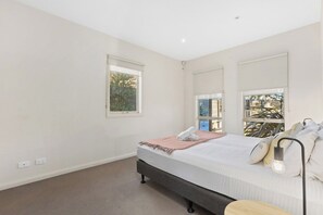Een slaapkamer met een bed, een bedlamp en een raam.