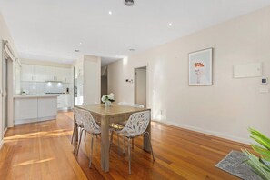 A modern kitchen with white cabinets and a wooden dining table with chairs.