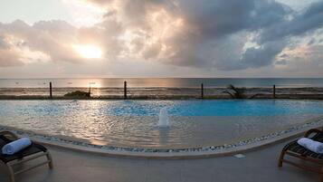 A swimming pool with a view of the sea and a cloudy sky.