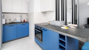 Een moderne keuken met blauwe kastjes, een ingebouwde oven en een grijze aanrechtblad.