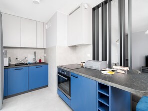 Eine moderne Küche mit blauen Schränken, einem eingebauten Backofen und einer grauen Arbeitsplatte.