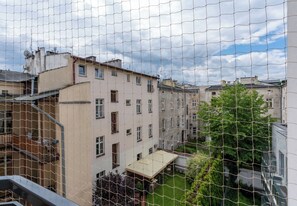 A residential building with multiple windows, a balcony, and a garden area visible through a wire mesh. - Kamienica Pod Czaplą Heritage Apartment (Kraków)