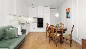 Una cocina moderna con armarios blancos, una mesa de comedor con sillas y un sofá verde.