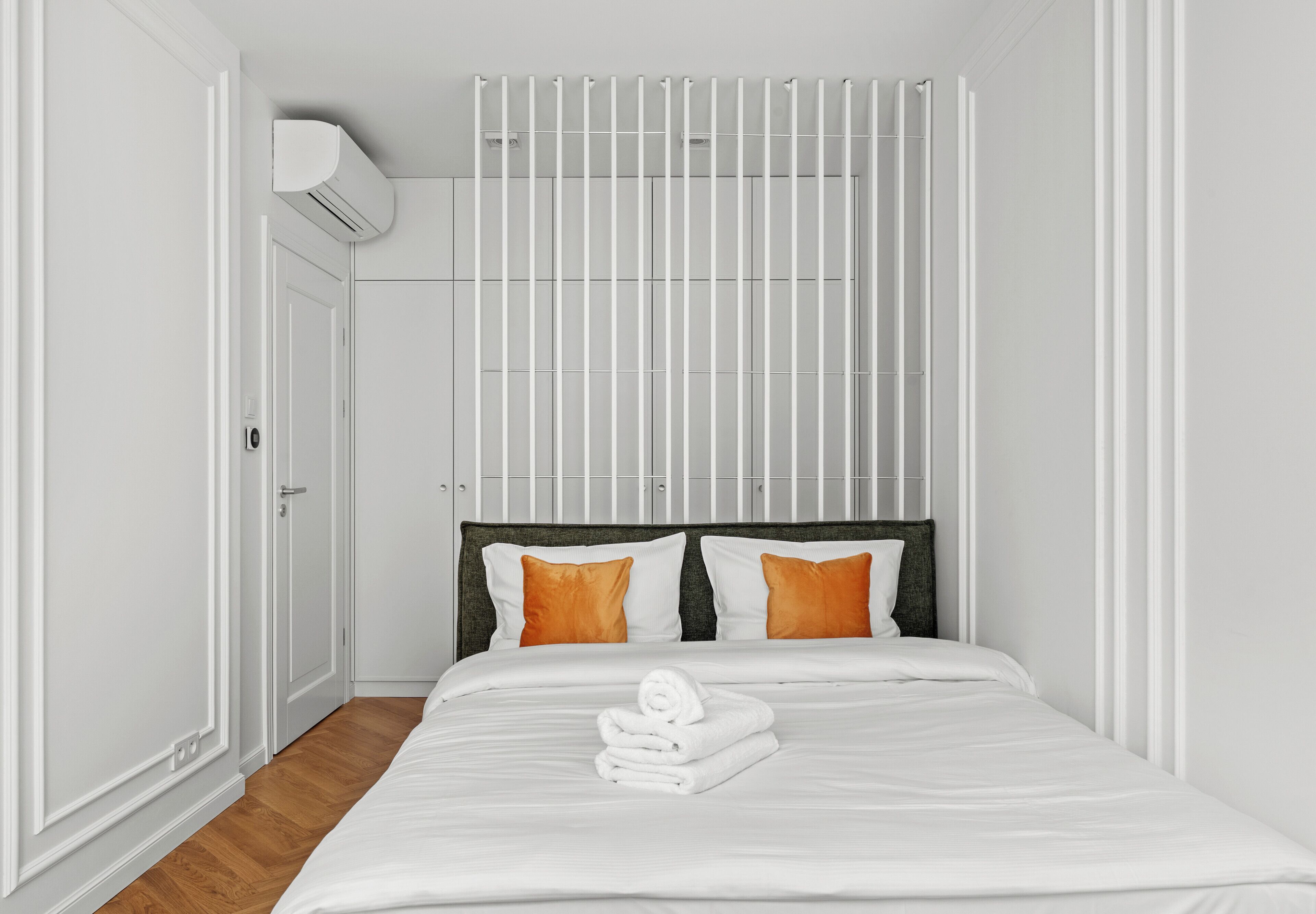 A hotel room with a bed, white walls, a window, and an air conditioning unit.