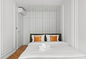 A hotel room with a bed, white walls, a window, and an air conditioning unit. - Kamienica Pod Czaplą Heritage Apartment (Kraków)