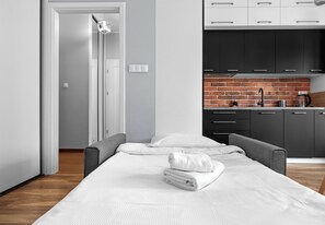 A modern room with a bed, a small kitchenette, and a door leading to another room. - Cracow Novum Apartment #104 (Kraków)
