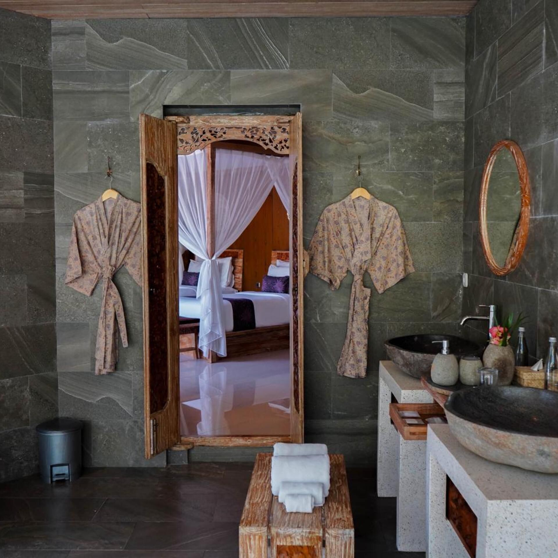 A bathroom with a large mirror, a wooden bench, and a sink with a basin.