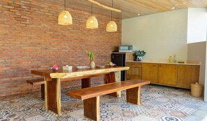 Una cucina con parete in mattoni, tavolo e panchetta in legno, luci a sospensione e un forno a microonde.