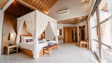 A spacious bedroom with a four-poster bed, a bedside table, a wooden bench, and a large window.