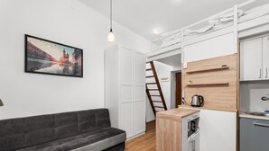 Ein kleiner Wohnbereich mit einer Couch, einer Küchenzeile und einem Stadtbild.