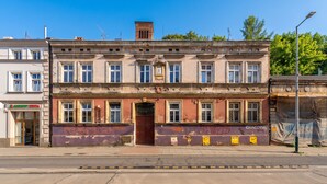 Ein dreigeschossiges Gebäude mit Eingang im Erdgeschoss und Fenstern im zweiten sowie dritten Obergeschoss.