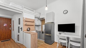 Eine kompakte Küchenzeile mit Einbauherd, Kühlschrank und Flachbildfernseher.