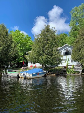 Una casa junto a un lago con un muelle y un bote.