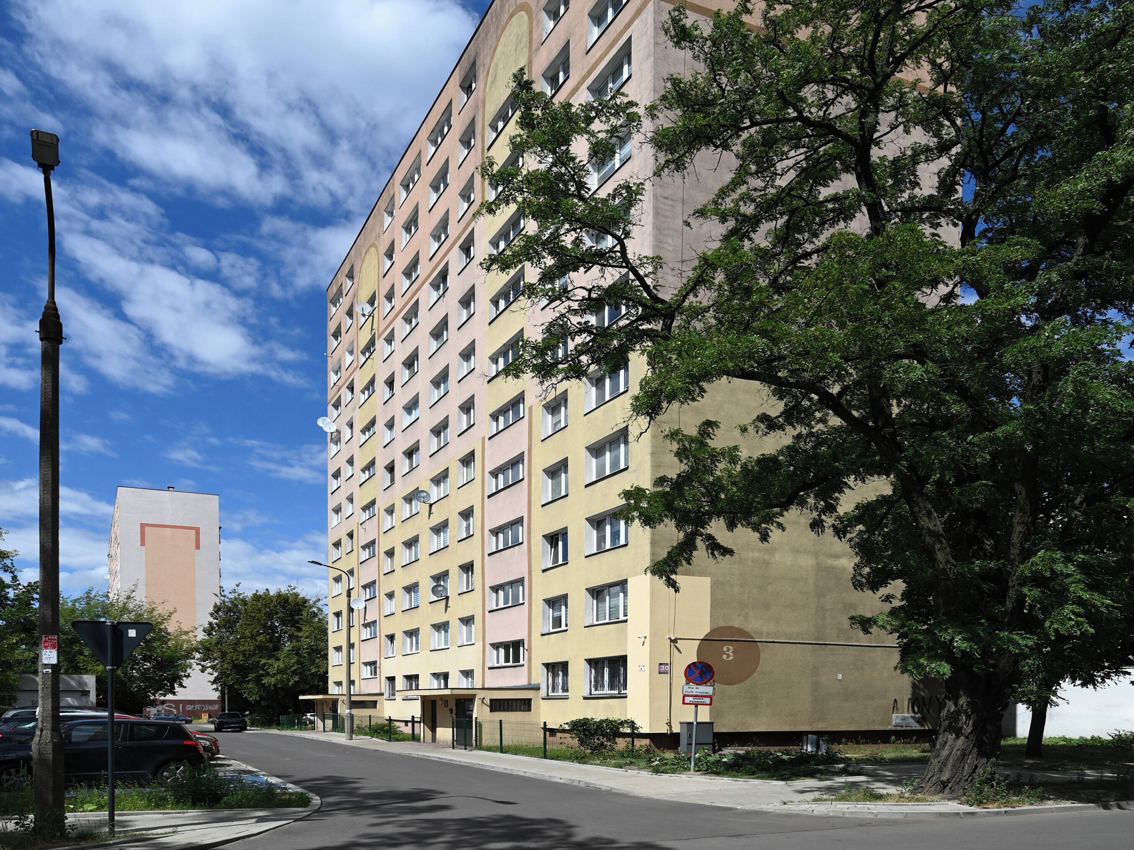 A multi-story residential building with a uniform facade, a street in front, and a clear sky.