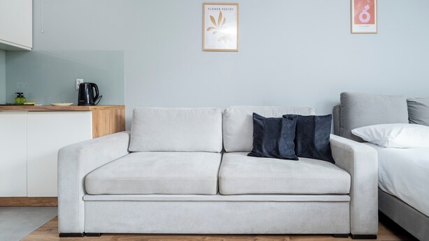 A modern living room with a sofa, a coffee table, and a kitchen area in the background. - Park Źródliska Harmony Studio (Łódź)