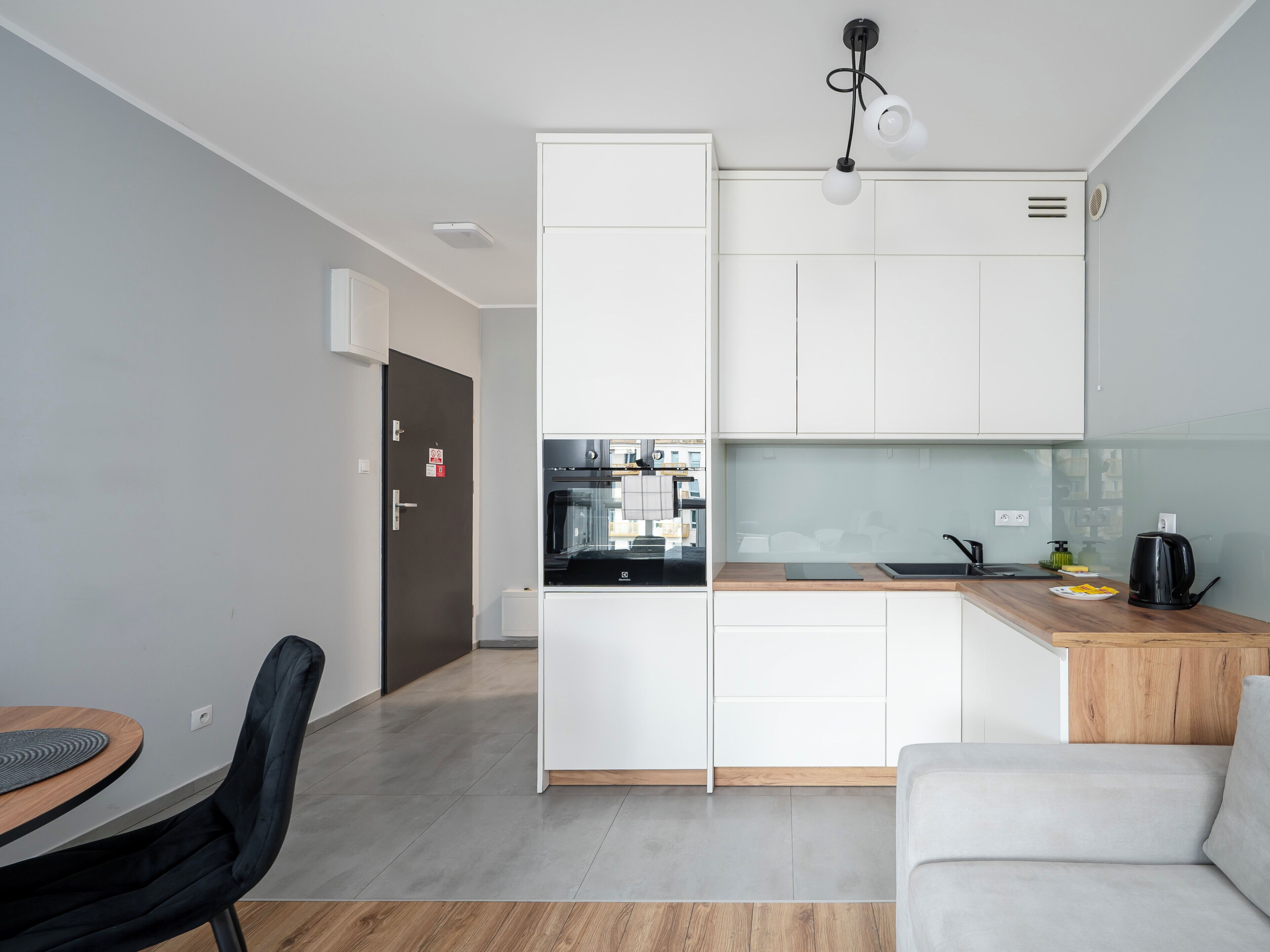 Una cucina moderna con mobili bianchi, piano cottura nero e un top in legno.
