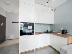 Een moderne keuken met witte kastjes, een inbouwoven, een spoelbak en een koffiezetapparaat.
