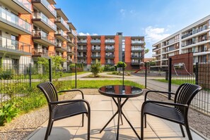 A courtyard with a round table and two chairs, surrounded by a fence, with apartment buildings in the background. - Cracow Novum Studio #124 (Kraków)