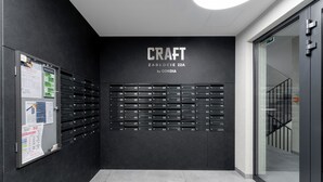 Ein modernes Interieur mit einem Wandregal, das 'CRAFT ZABLOCIE 22A by CORDIA' beschriftet, und einem Glastür-Eingang.