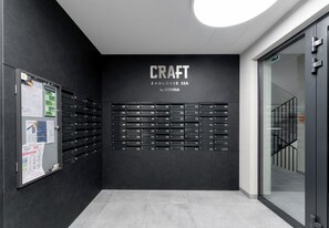 Ein modernes Interieur mit einem Wandregal, das 'CRAFT ZABLOCIE 22A by CORDIA' beschriftet, und einem Glastür-Eingang.