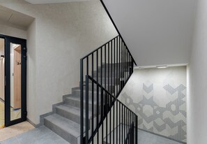 Un escalier avec des rampes noires menant à un palier agrémenté d’un mur ajouré.