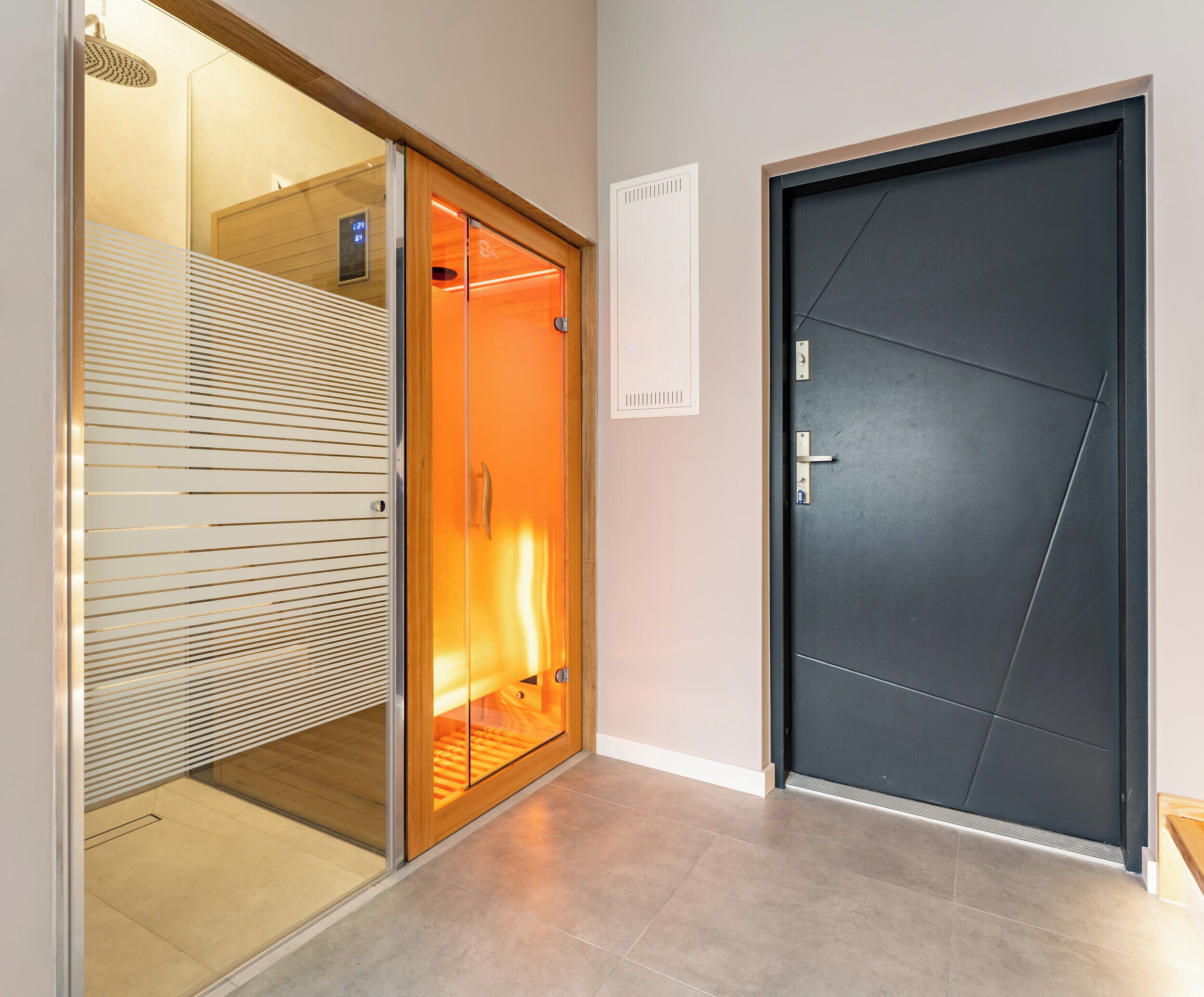 A modern hotel room with a sliding glass door, a dark door, and a light switch on the wall.