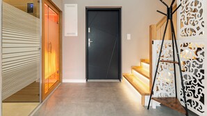 A modern interior with a black door, wooden staircase, and a decorative white partition. - Willa 28D Lakeside Retreat Łączyno (Łączyno)